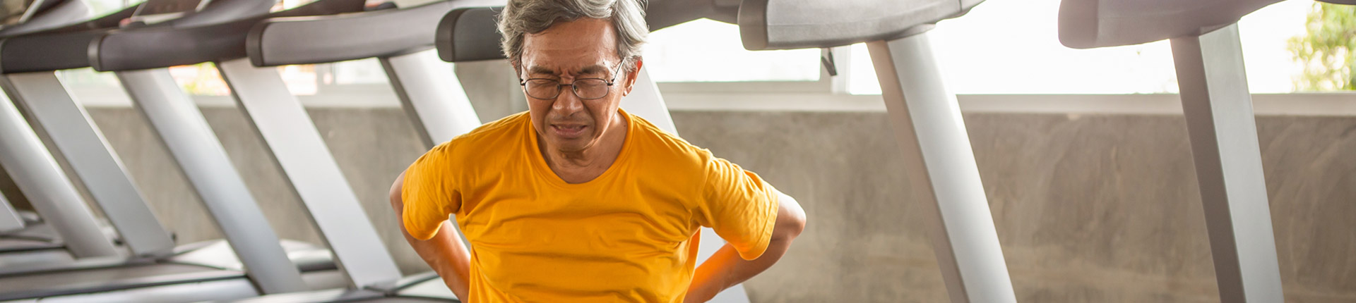 man on treadmill grasping back