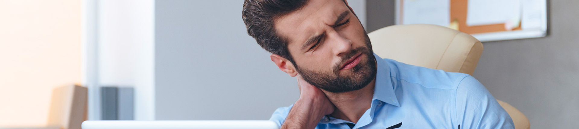 man with pain expression and hand on neck